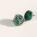 Green marbled round polymer clay studs with parallel curved ridges, angled view