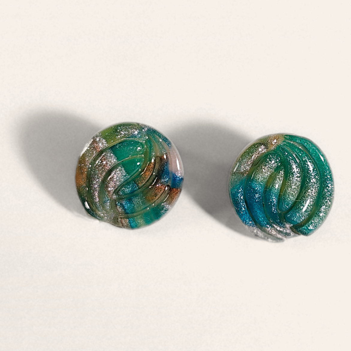 Green marbled round polymer clay studs with parallel curved ridges, front view