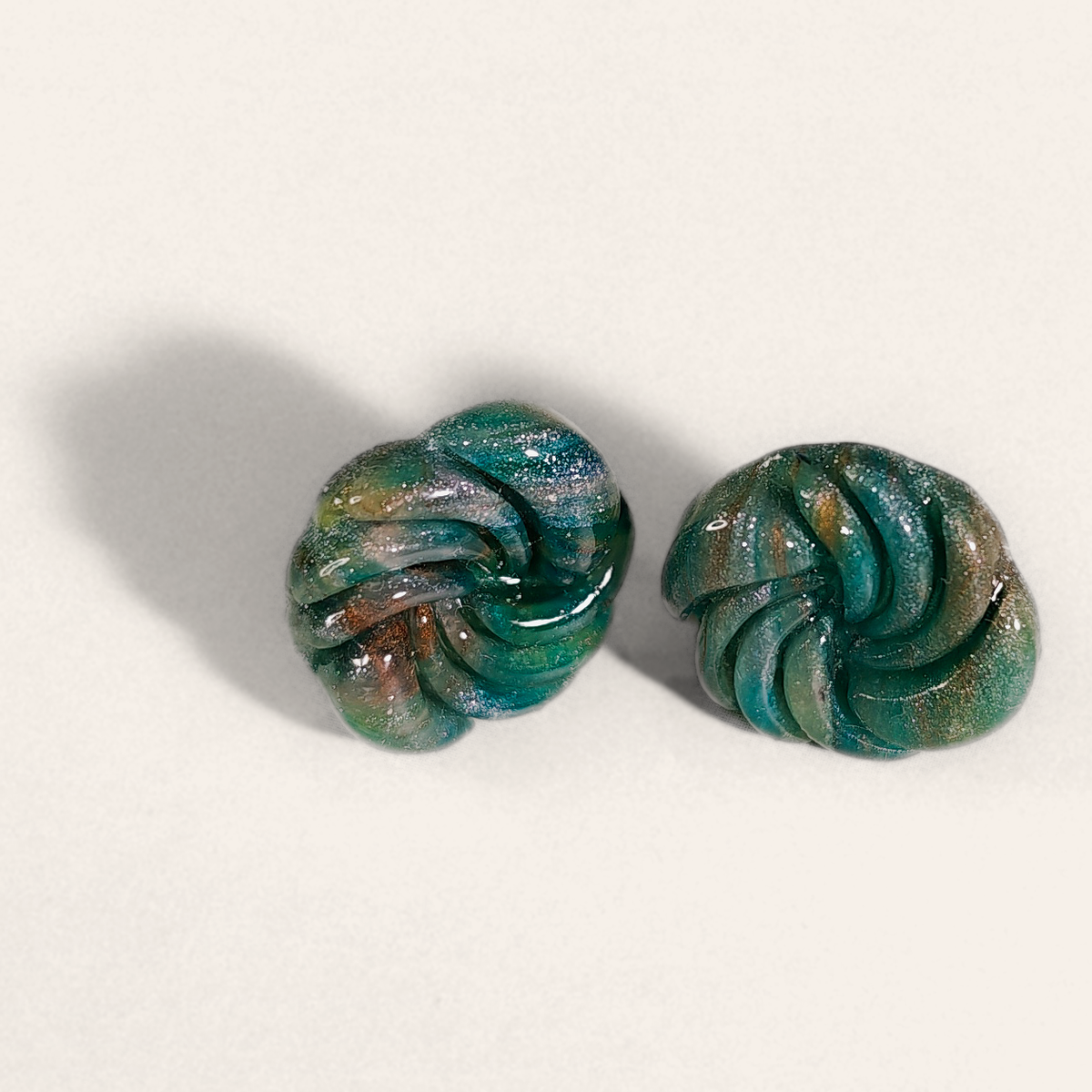 Green marbled round polymer clay studs with spiral ridges, front view